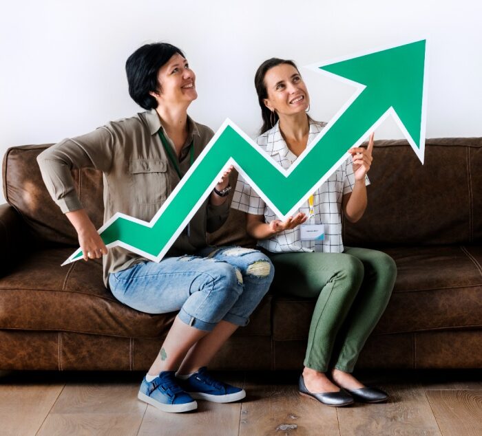 Duas pessoas felizes segurando uma seta verde em formato de gráfico de crescimento. Duas pessoas felizes segurando uma seta verde em formato de gráfico de crescimento.