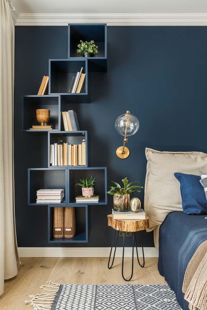 Nichos coloridos fixados na parede de um quarto de casal, com livros, plantas e objetos decorativos em composição leve. Nichos coloridos fixados na parede de um quarto de casal, com livros, plantas e objetos decorativos em composição leve.