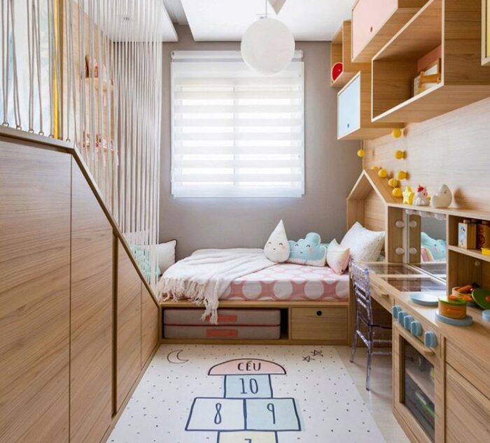 Um bom exemplo de como a multifuncionalidade pode ajudar na organização e adaptação do quarto infantil ao longo dos anos. Quarto infantil com cama com gavetas embutidas e prateleiras coloridas.