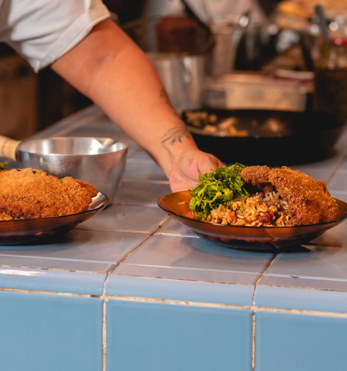 A imagem retrata o Mercado Novo, ponto cultural e gastronômico revitalizado que atrai moradores e visitantes, fortalecendo o estilo de vida urbano e criativo no entorno do Barro Preto. Pratos produzidos no Mercado Novo de Belo Horizonte