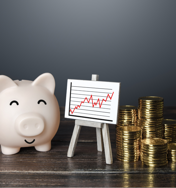 Cofrinho e pilhas de moedas ao lado de gráfico de crescimento, representando valorização imobiliária e renda com aluguel.